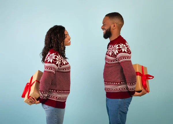 Mencintai african american pria dan wanita memegang hadiah Natal di belakang punggung mereka, bertukar hadiah, latar belakang biru — Stok Foto