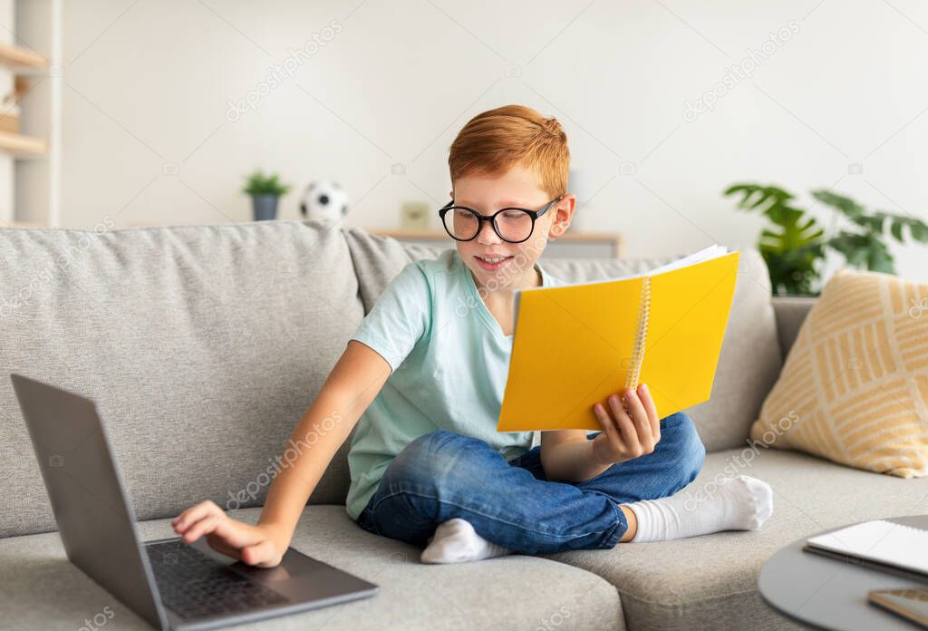 Smart school boy with glasses doing homework at home