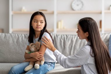 Aile içi çatışma kavramını çözmek. Genç Asyalı anne küçük kızı rahatlatıyor ve konuşmaya çalışıyor, boşluğu kopyalıyor.