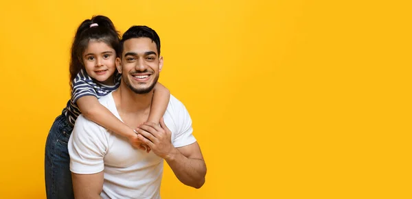 Feliz jovem Oriente Médio pai e bonito pequena filha posando sobre fundo amarelo — Fotografia de Stock