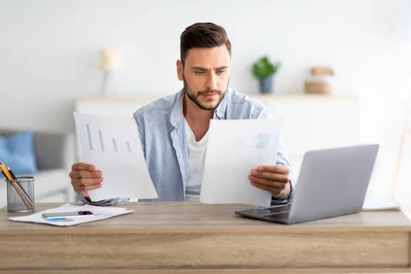 Homme entrepreneur indépendant millénaire travaillant avec des papiers au bureau à domicile, vérifiant les rapports financiers annuels, espace libre — Photo