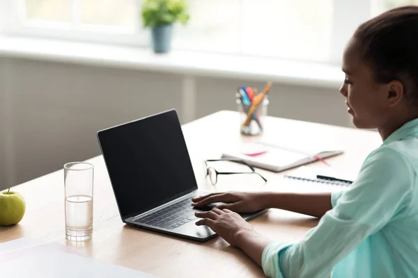 Adolescente afroamericana chica estudiante escribiendo en el ordenador portátil con pantalla vacía maqueta y estudiar — Foto de Stock