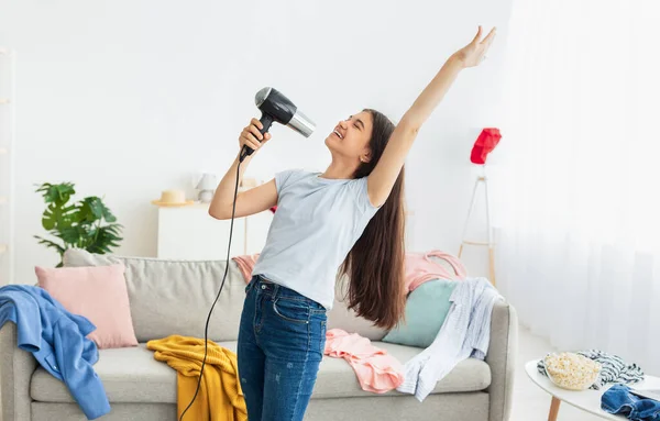 Retrato de adolescente indiano dançando e cantando karaoke, usando secador de cabelo como microfone, tendo concerto doméstico — Fotografia de Stock