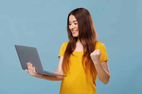 Emocjonalna młoda kobieta z laptopem podnoszącym pięść — Zdjęcie stockowe