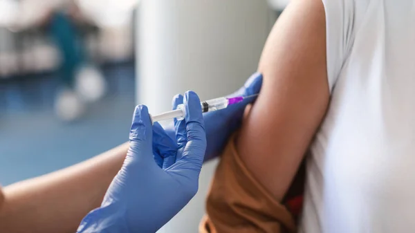 Ung kvinna som får vaccininjektion sittandes med doktor Indoor — Stockfoto