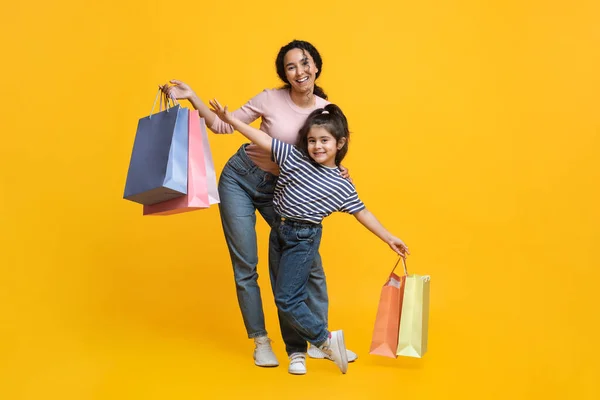 Ir de compras con mamá. Feliz madre de Oriente Medio e hija pequeña llevando bolsas de compras —  Fotos de Stock