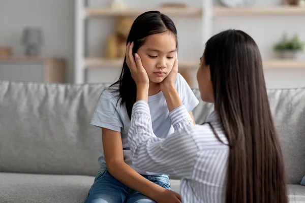 Concepto de malentendido familiar. Joven asiática madre calmando su ofendido hija después de disputa, espacio libre — Foto de Stock