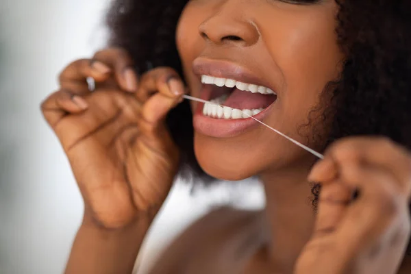 Nerozpoznatelná Afro žena čistí zuby zubní nití doma, detailní záběr. Ústní hygiena, wellness, zdravý životní styl — Stock fotografie