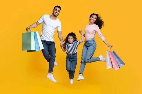 Groot Shopping Concept. Overblij Arabische familie van drie springen met shopper tassen — Stockfoto