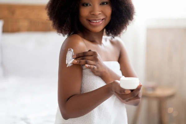 Atractiva joven Afro mujer aplicando crema en el cuerpo, mimándose después de bañarse o ducharse en casa —  Fotos de Stock