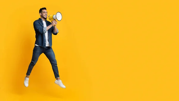 Homme arabe émotionnel sautant avec mégaphone, espace de copie — Photo