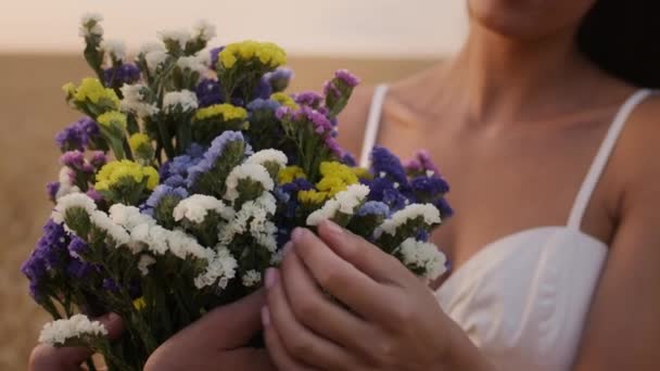 Romantik bir çift açık havada çayırlık çiçekleri tutuyor ve kokluyor. — Stok video