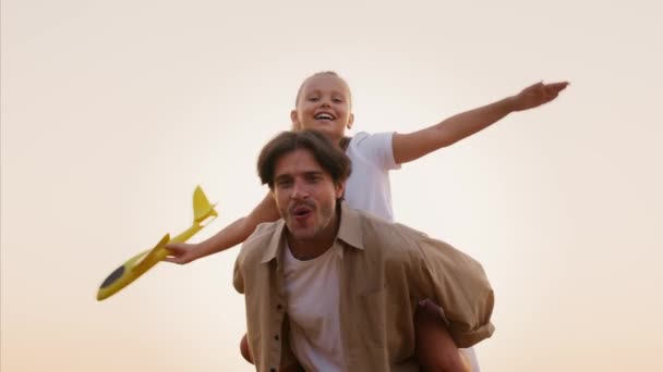 Alegre jovem pai e filha se divertindo ao ar livre, jogando com avião brinquedo — Vídeo de Stock