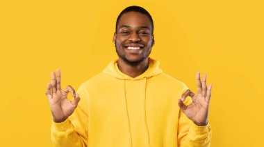 Siyah adam, tamam işareti yapıyor Stüdyoda duruyor, Sarı Arkaplan