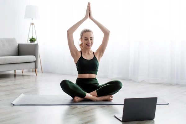 Satisfied caucasian beautiful young blonde woman practicing yoga in lotus position, exercising at home — Stock Photo, Image