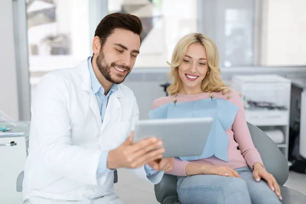 Vrolijke man tandarts bespreken behandeling met mooie dame patiënt — Stockfoto