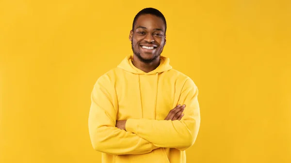Успешный Black Millennial Guy Crossing Hands Over Yellow Studio Background — стоковое фото
