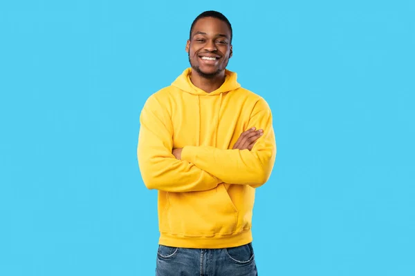 Afrikai amerikai Y-generációs Guy mosolygós pózol Crossing Hands, kék háttér — Stock Fotó