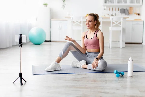 Sonriente europea bastante millennial rubia fitness blogger mujer mirando webcam y haciendo ejercicio — Foto de Stock