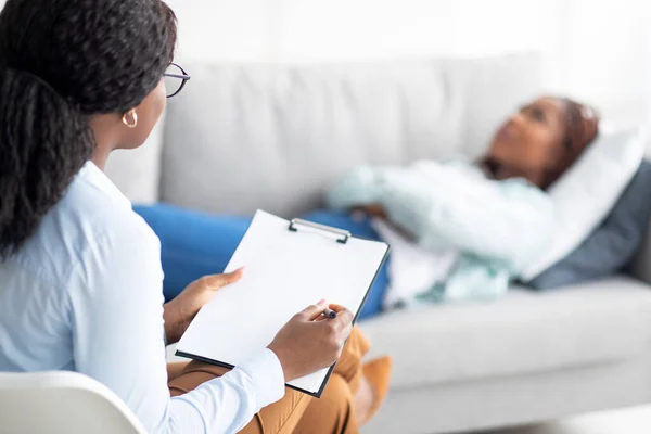 Zwarte vrouwelijke patiënt liggend op de bank bij psychologen kantoor, het hebben van sessie met counselor, het krijgen van depressie behandeling — Stockfoto