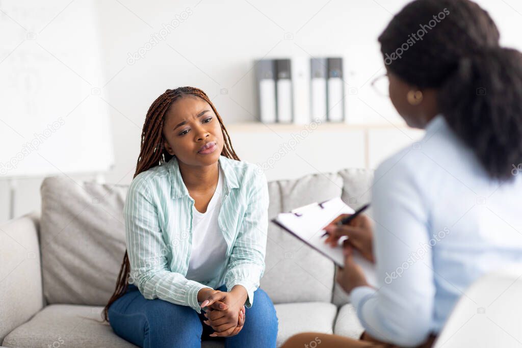 Anxious black woman having counseling session with therapist at clinic, receiving professional help and support