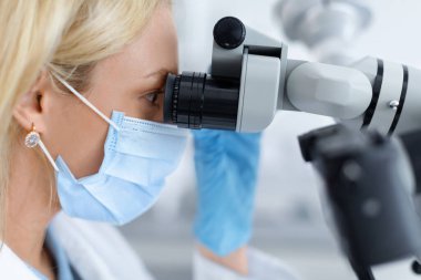 Dişçi, diş sağlığı kliniğinde modern ekipman kullanıyor.