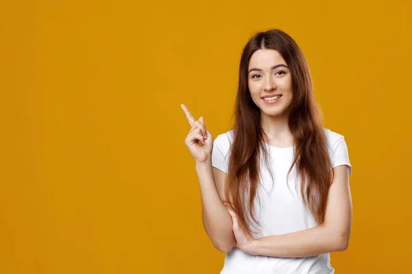 Senhora alegre posando sobre fundo colorido, apontando para o espaço de cópia — Fotografia de Stock