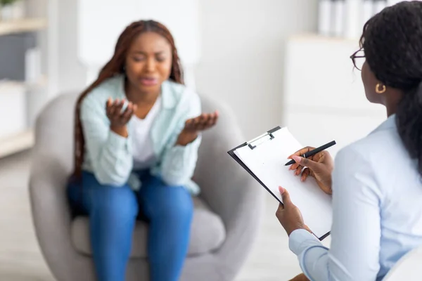 Depressed black woman consulting psychologist, expressing negative emotions at mental clinic, copy space — Stock Photo, Image
