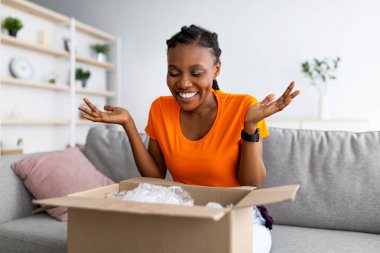 Çevrimiçi dağıtım, uzaktan alışveriş. Positif siyah kadın karton paketleri açıyor, evden satın almaktan memnun.