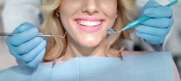 Fechar o sorriso do paciente feminino e mãos de dentista com ferramentas — Fotografia de Stock