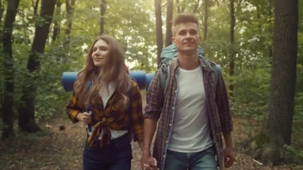 Un par de ocio. Joven feliz hombre y mujer caminando juntos en el bosque de otoño, caminando y tomados de la mano, seguir disparo — Vídeos de Stock