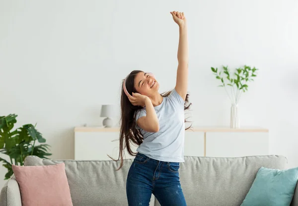 Alegre chica adolescente india con auriculares inalámbricos bailando con música encantadora en casa — Foto de Stock