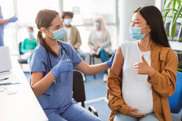 Vakcinovaná těhotná asijská dáma a lékař gesto palec nahoru na klinice — Stock fotografie