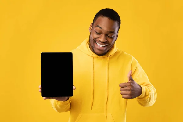 Africano chico mostrando pantalla de la tableta gestos Pulgares hacia arriba sobre fondo amarillo — Foto de Stock