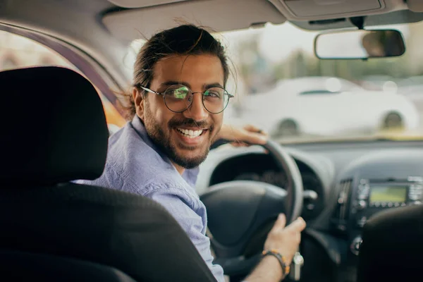 Fröhlicher Taxifahrer aus dem Mittleren Osten blickt auf Rückbank und lächelt — Stockfoto