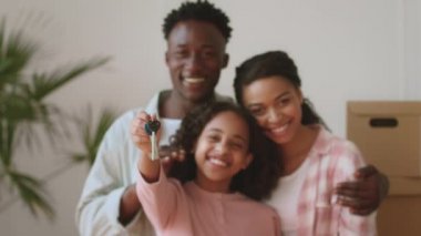 Gayrimenkul ve genç aileler. Afrika kökenli Amerikalı anne ve baba ve kız kameraya sarılıp gülümsüyorlar.