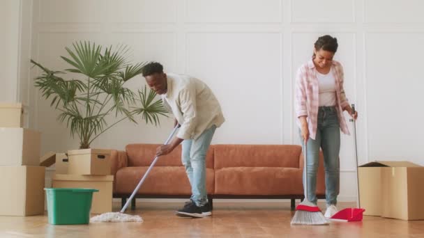 Nettoyage de déménagement. Jeune amd afro-américaine gaie et femme essuyant et lavant le sol dans un nouvel appartement ensemble — Video