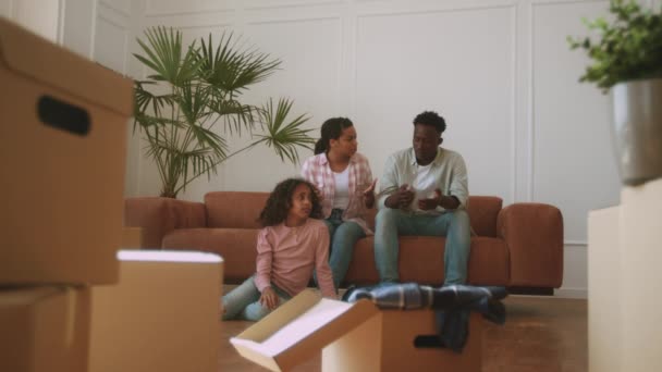 긴장 한 젊은 아프리카 계 미국인 부모들 이 새 집에서 싸우고 있습니다. 슬픈 어린 소녀가 판지 상자 사이 바닥에 앉아 있습니다. — 비디오