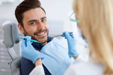 Kadın dişçi, neşeli adamın tedavisini yapıyor.