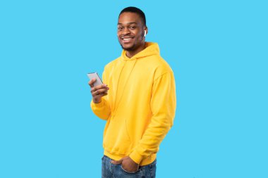 Mavi Arkaplan Üzerine Kulaklık Giyen Akıllı Telefon kullanan Afrikalı Amerikalı Adam