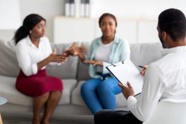 Hüsrana uğramış LGBT lezbiyen çifti klinikte psikologla tartışırken.