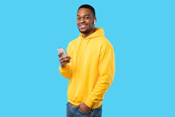 Afro-americano Usando Smartphone Usando Auriculares Sobre Fondo Azul —  Fotos de Stock