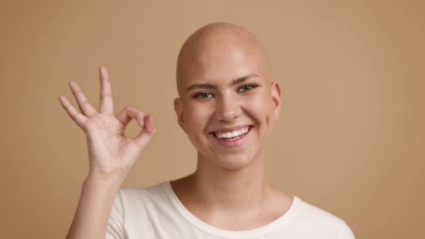 Mujer calva gestos bien signo sonriente de pie sobre fondo beige — Vídeos de Stock