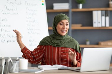 Gemiyi gösteren Müslüman İngilizce öğretmeni öğrencilere ders veriyor.
