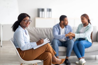 Gülümseyen siyah kadın psikolog ve binlerce yıllık Afro çift klinikte etkili bir terapiden sonra barışıyorlar.