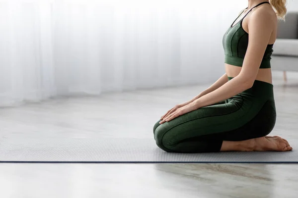Oigenkännlig lugn kaukasisk tusenårig kvinna utövar yoga ensam, sitter på mattan hemma — Stockfoto