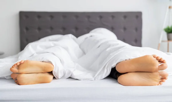 Sexuální problémy. Mladý muž a jeho přítelkyně leželi zády k sobě v posteli, zblízka na nohou — Stock fotografie