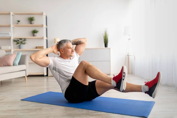 Kilitleme sırasında spor. Olgun bir adam yoga minderinde spor yapıyor, tüm vücudunu evde çalıştırıyor. — Stok fotoğraf