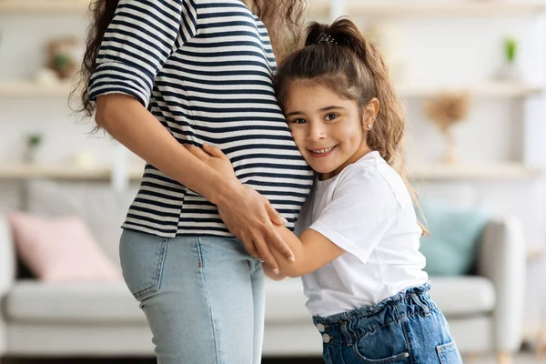 Linda niña abrazando a su madre embarazada gran vientre — Foto de Stock