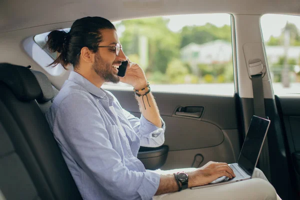 Positiv arabisk man frilansare arbetar online medan du sitter i taxi — Stockfoto